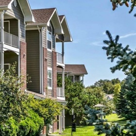 an apartment with grass and trees in front