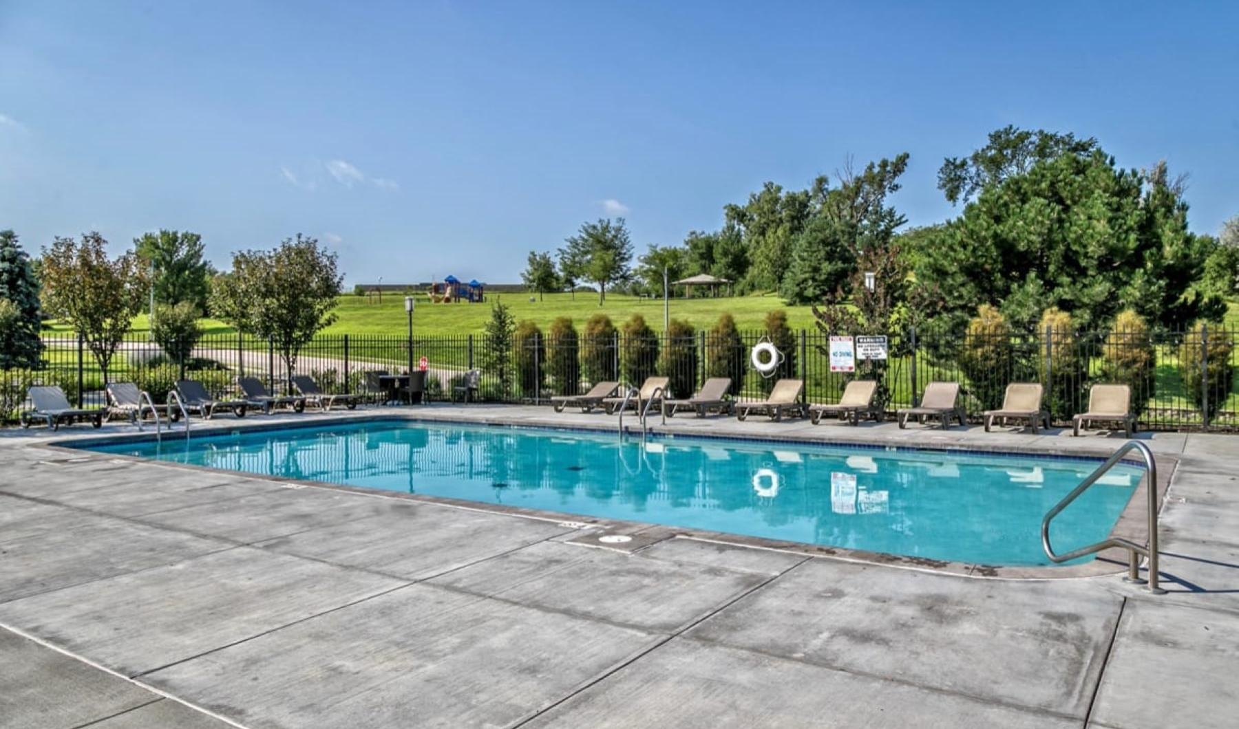 a swimming pool with a fence and trees in the background